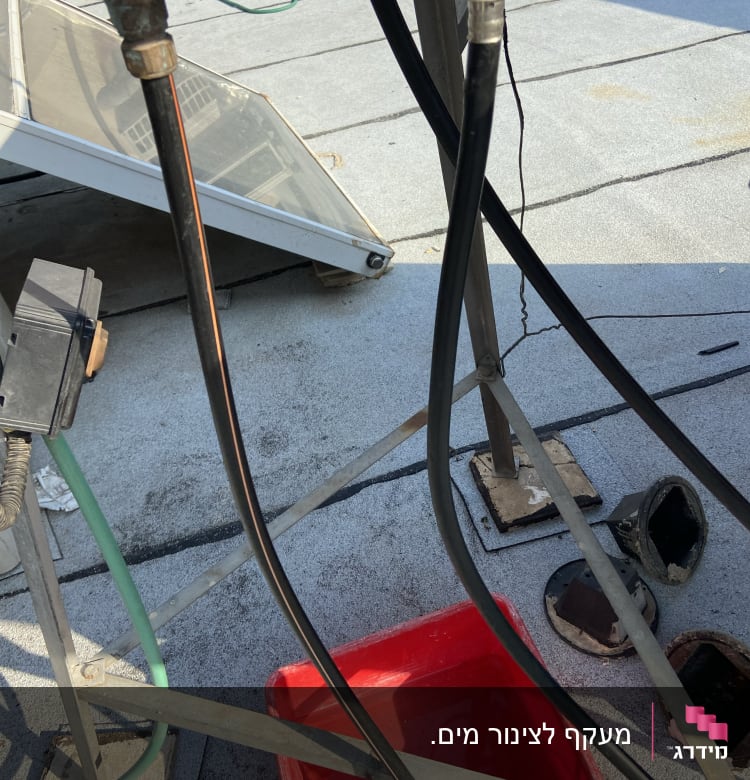 צינורות מים מחוברים לברזים מעל דלי אדום